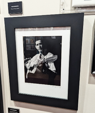 Framed photograph of Oscar Brand playing guitar on display